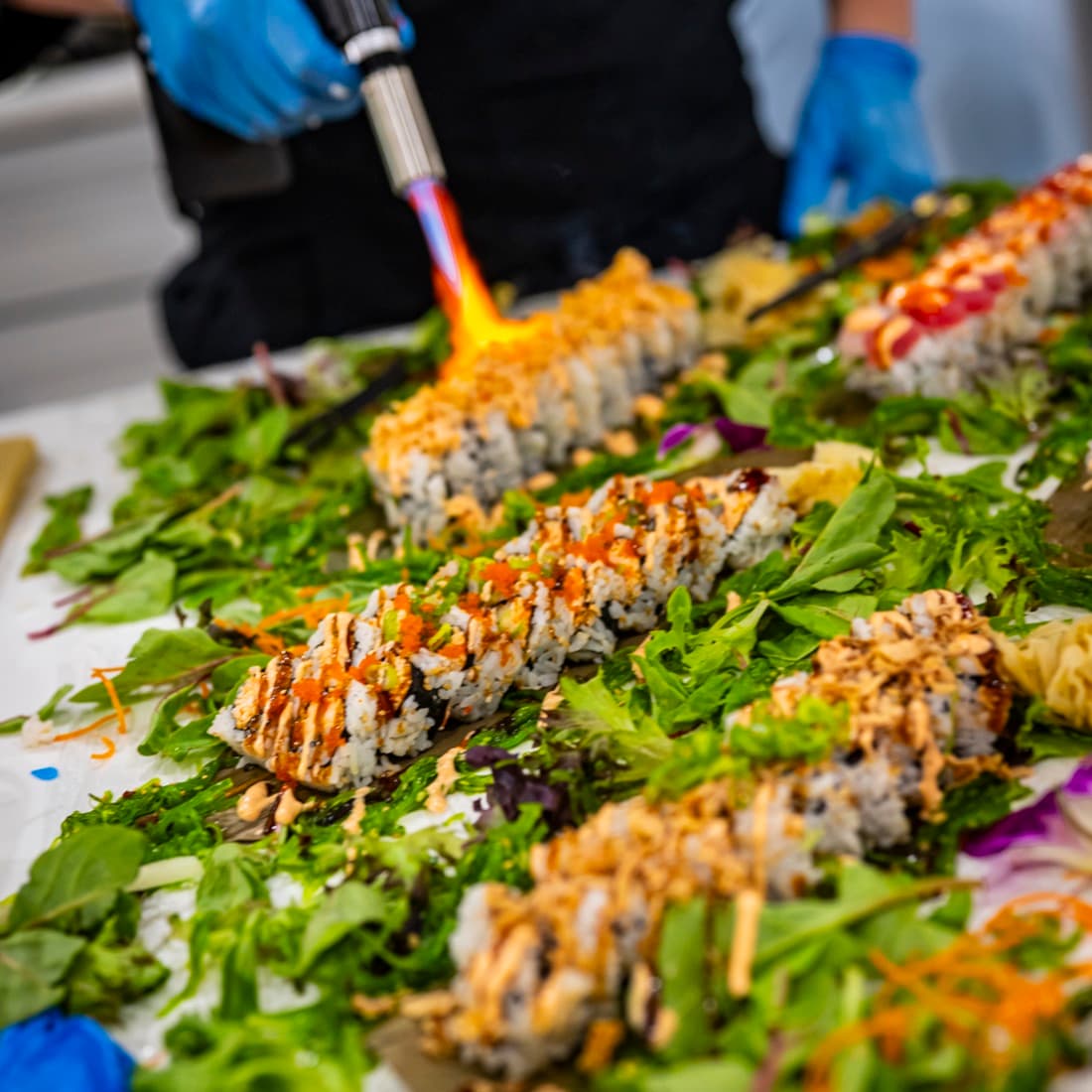 Chef torching a specialty roll at a private sushi event in Gainesville.