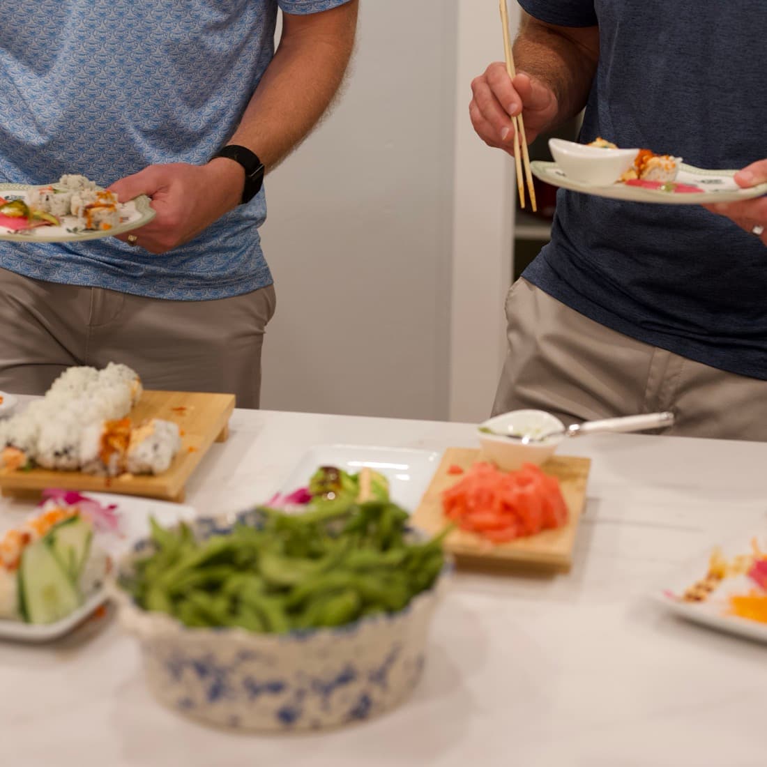 Guests filling their plates at the counter during an in-home sushi event.