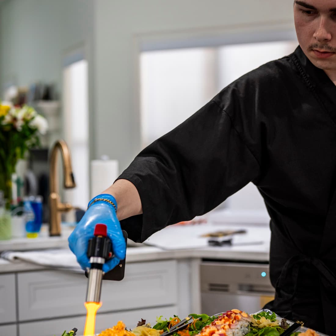 Chef torching sushi to order during an in-home omakase event.