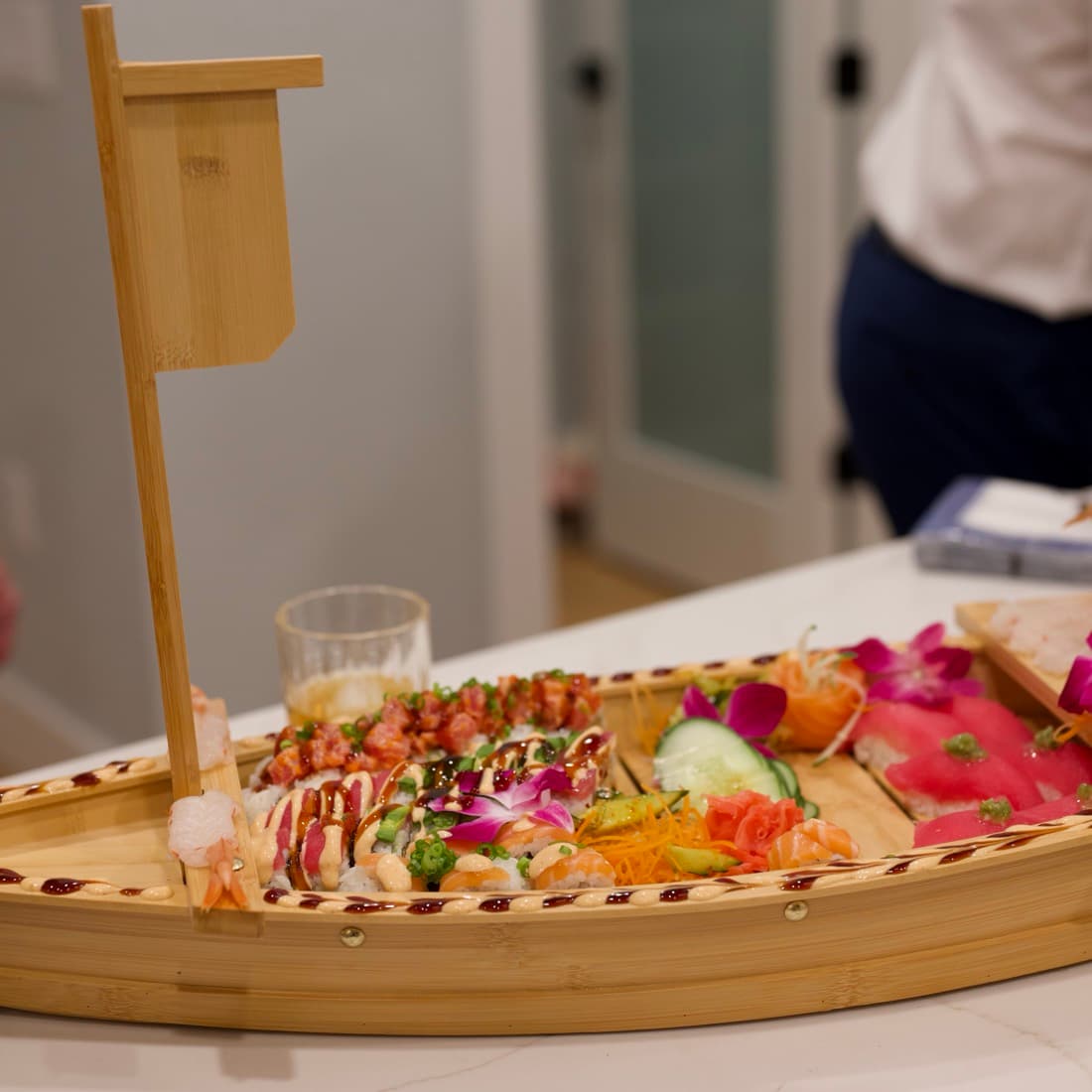 The whole sushi boat on the counter, loaded and garnished with orchids.