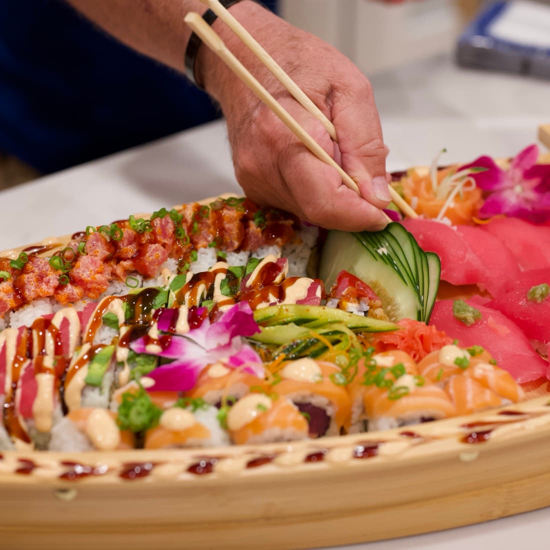 A guest picking a roll from the sushi boat with chopsticks.