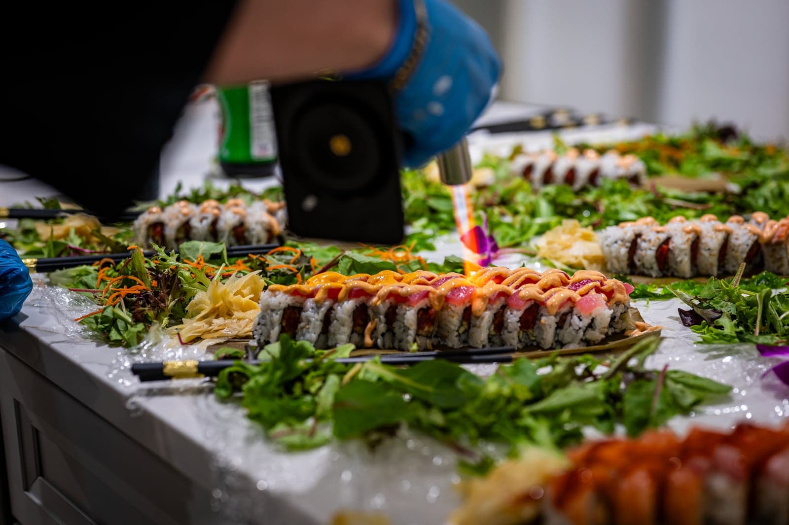 A chef torching a colorful spread of specialty rolls at a Sonakase event.