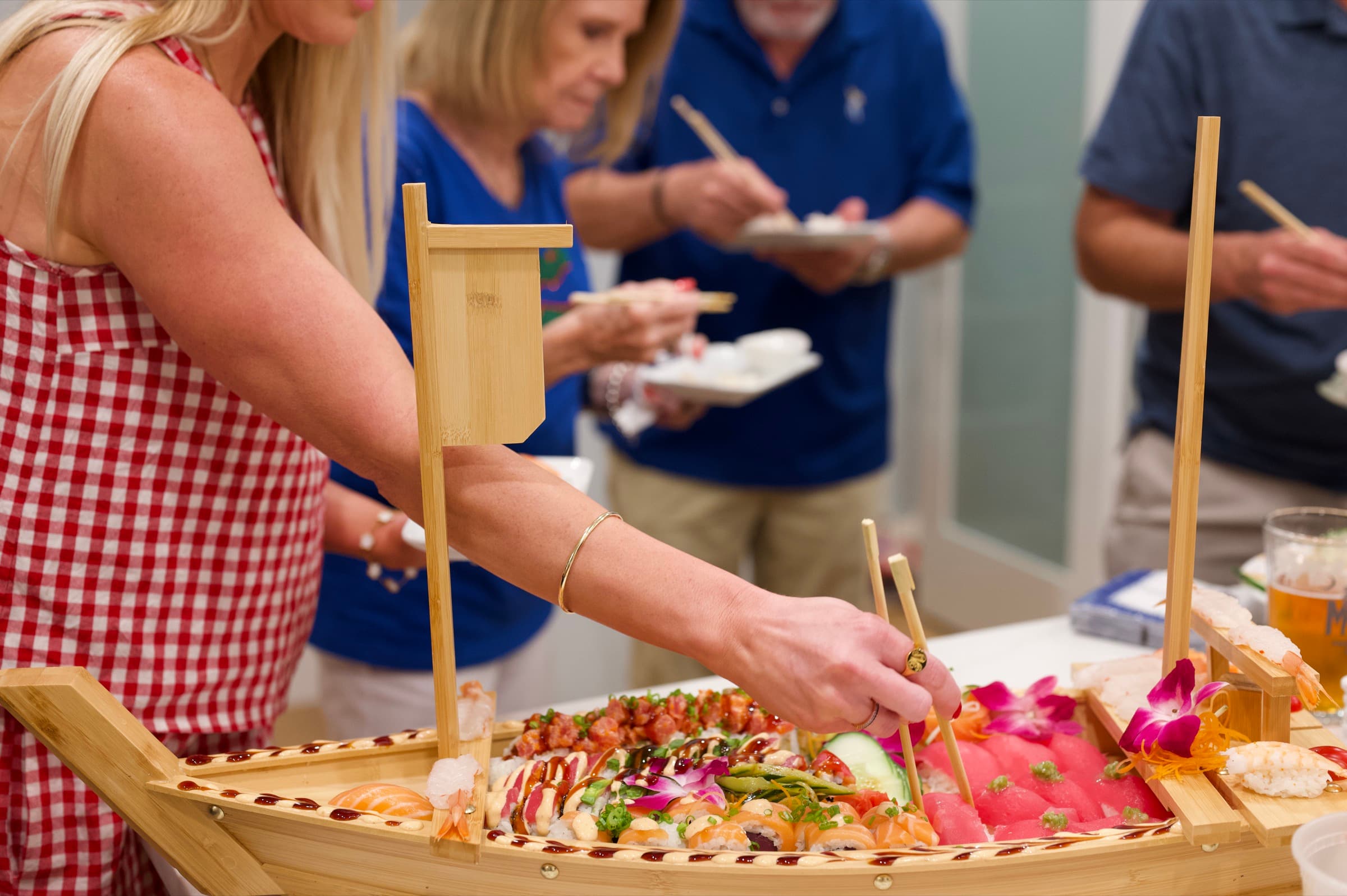 Guests serving themselves from the sushi boat with chopsticks.